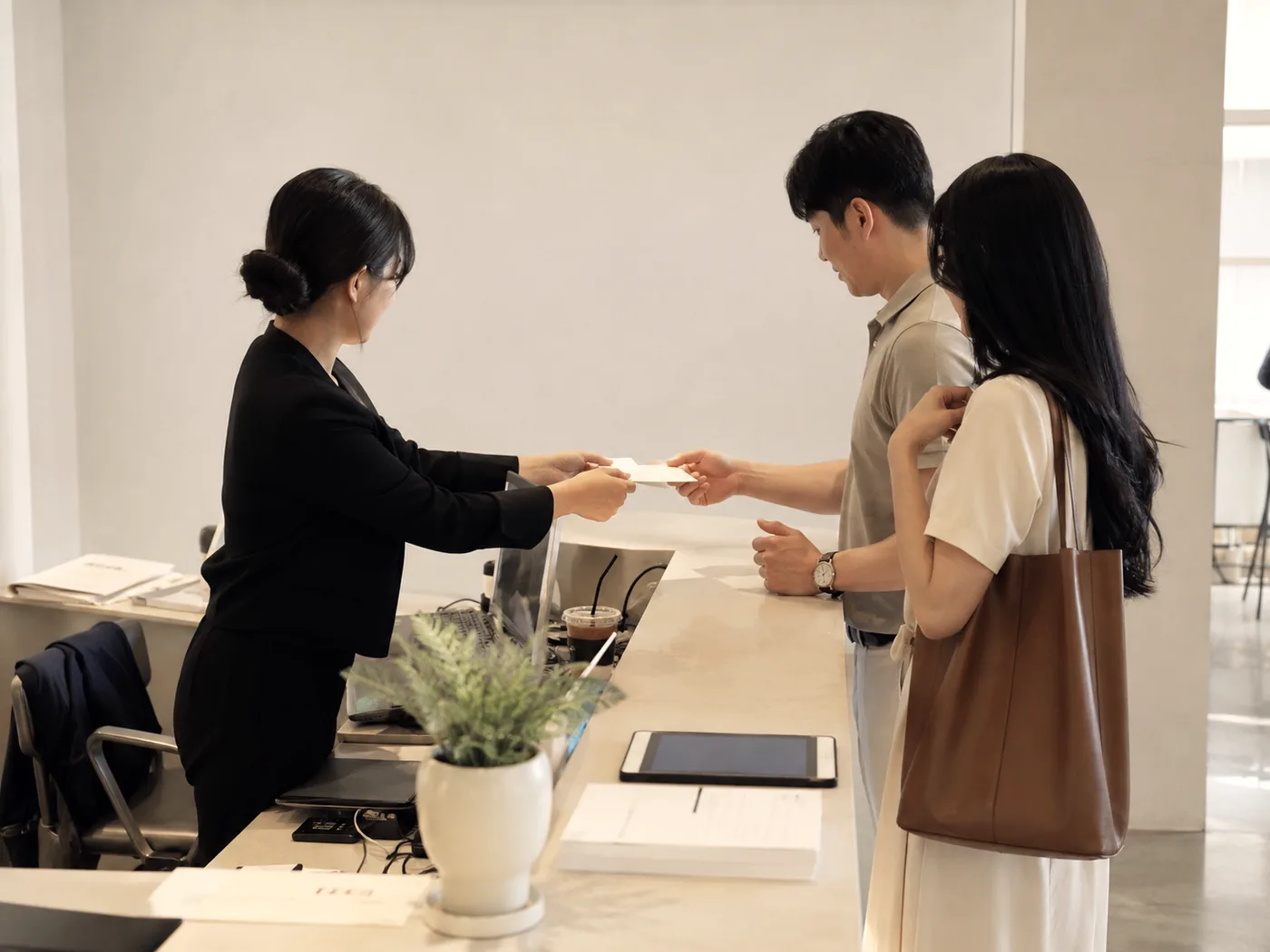 접수 데스크에서 담당자가 접수증을 건네는 모습, 뒤에 기다리는 줄이 없다